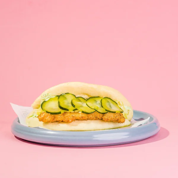 Panino al vapore, cotoletta di orata, salsa tzatziki, verza marinata e cetriolini in carpione